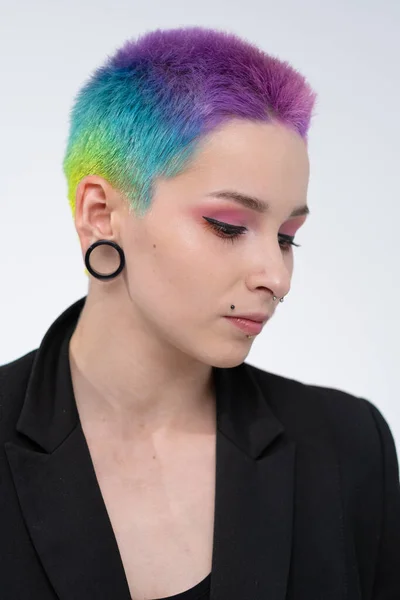 Uma jovem menina bonita com cabelo curto colorido. Espalhe coloração brilhante e maquilagem criativa. Piercing na cara. Uma jaqueta preta. — Fotografia de Stock