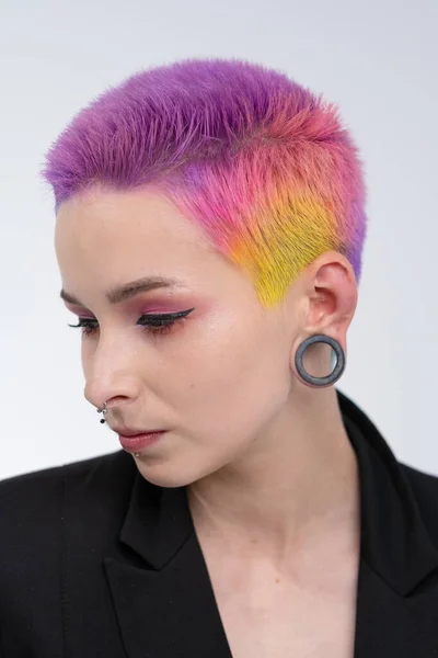 Uma jovem menina bonita com cabelo curto colorido. Espalhe coloração brilhante e maquilagem criativa. Piercing na cara. Uma jaqueta preta. — Fotografia de Stock