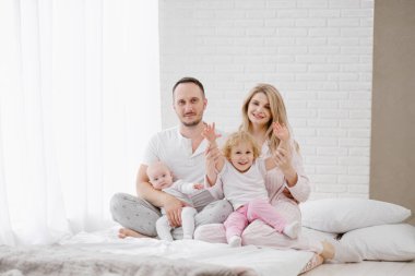 Beyaz bir evde iki çocuklu, genç bir Kafkas ailesi. Ev kıyafetleri.