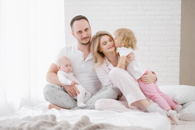 Beyaz bir evde iki çocuklu, genç bir Kafkas ailesi. Ev kıyafetleri.