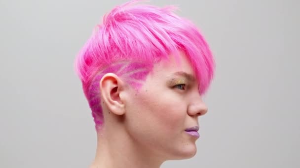短い散髪とピンクの髪を持つ若い美しい女の子。同性愛者のレズビアンモデルは白い背景にポーズ. — ストック動画