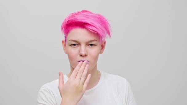 Joven chica hermosa con un corte de pelo corto y cabello rosa. Una modelo lesbiana homosexual posa sobre un fondo blanco. — Vídeos de Stock