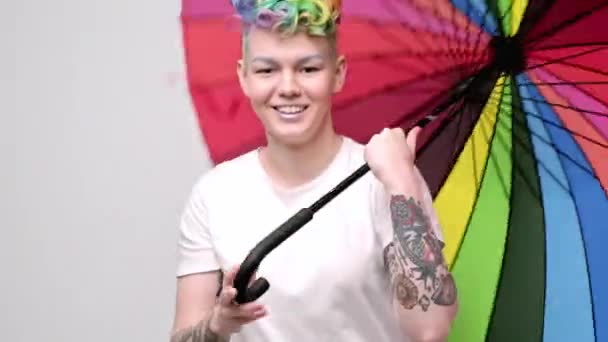 Schöne junge Mädchen mit gefärbten Haaren und einem Kurzhaarschnitt. Öffnet einen leuchtend farbigen Regenschirm und verdreht ihn. — Stockvideo