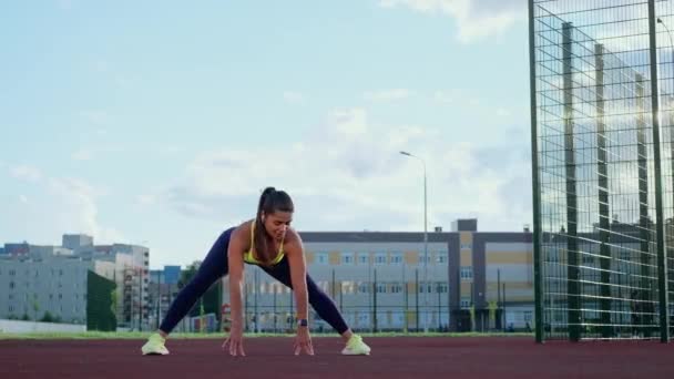 Egy fiatal sportos lány nyújtózkodik futás előtt, és fitnesz edzést tart a szabadban.. — Stock videók