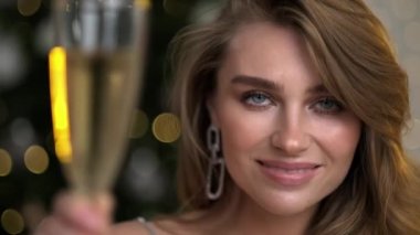 Elinde bir bardak şampanyayla genç ve güzel bir sarışın kadın gülümsüyor, seviniyor, kutluyor ve şereflendiriyor..