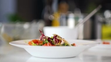 Erkek şef restoran mutfağında sebze ve kırmızı balık salatası hazırlıyor. Yakın plan..