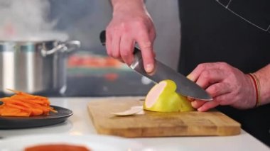 Erkek şef restoranların mutfağında bir tahta kesme tahtasıyla greyfurt temizler ve keser. Yemek pişirme.