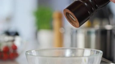 Şef sosu salata için hazırlar, biber ve tuzu değirmenden cam bir kaseye koyar..