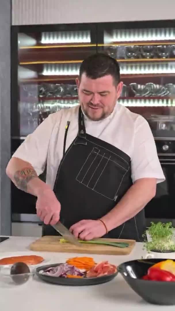 Le chef masculin coupe les oignons sur une planche à découper en bois dans la cuisine du restaurant. Cuisson. — Video