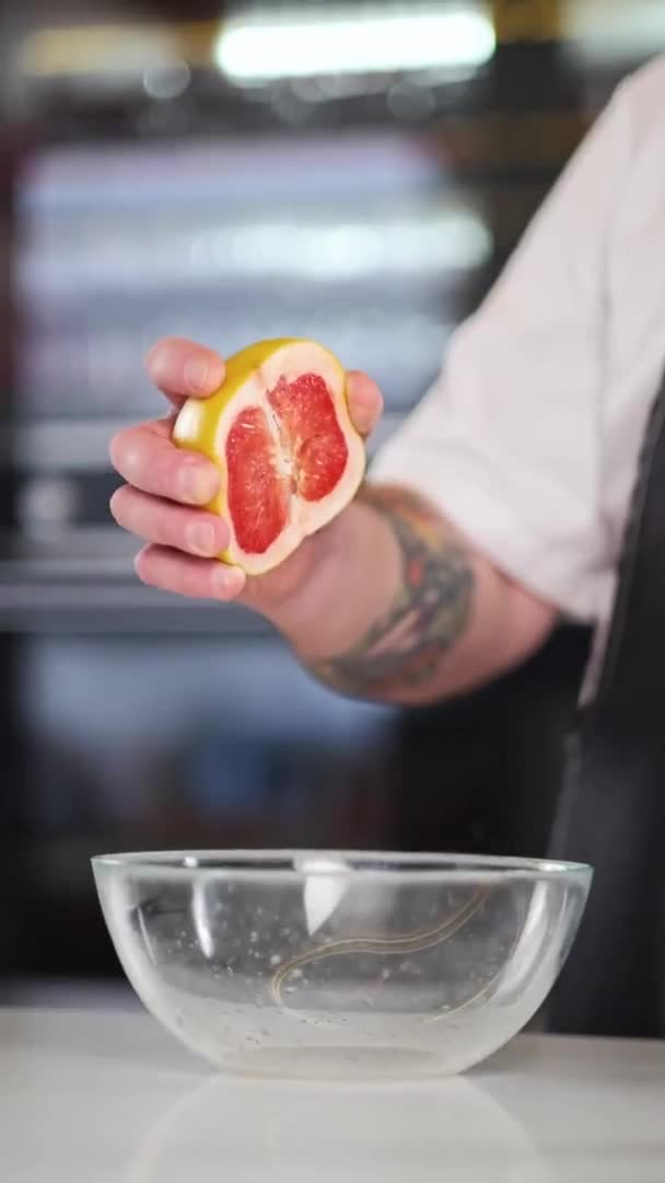 El chef masculino exprime el zumo de pomelo en un recipiente de vidrio. Preparación de aderezo para ensaladas. Restaurante profesional cocina, cocina. — Vídeos de Stock