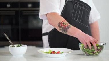 Erkek şef farklı türde marul yaprakları karıştırır. Restoranın mutfağında yemek pişirmek..