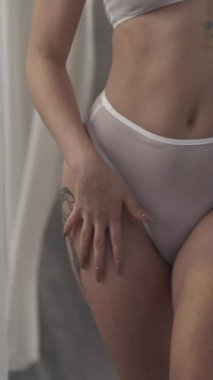 Uzun kıvırcık kızıl saçlı, beyaz şeffaf iç çamaşırlı güzel bir kız. Bir kadın, rüzgarda çırpınan beyaz kumaşların arka planında poz verir..