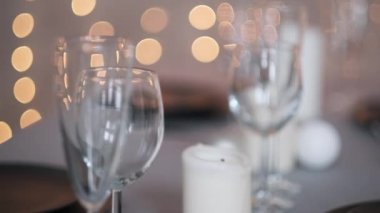 Şenlikli servis edilen yemek masası. Güzel yemekler, masa örtüleri, şarap bardakları ve gri tabaklar. Mumlar ve arka planda bir çelenk. Minimalist yemek odası dekorasyonu. Noel.