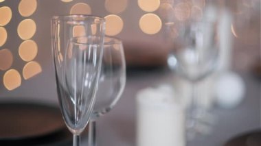 Şenlikli servis edilen yemek masası. Güzel yemekler, masa örtüleri, şarap bardakları ve gri tabaklar. Mumlar ve arka planda bir çelenk. Minimalist yemek odası dekorasyonu. Noel.