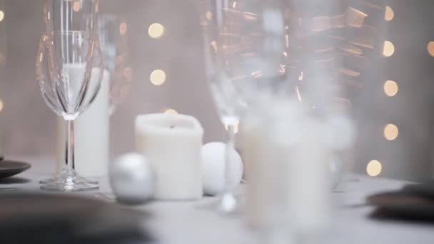 Mesa de jantar festiva servido. Belos pratos, toalhas de mesa, copos de vinho e pratos cinzentos. Velas e uma grinalda ao fundo. Decoração minimalista da sala de jantar. Natal.. — Vídeo de Stock