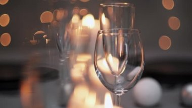 Şenlikli servis edilen yemek masası. Güzel yemekler, masa örtüleri, şarap bardakları ve gri tabaklar. Mumlar ve arka planda bir çelenk. Minimalist yemek odası dekorasyonu. Noel.