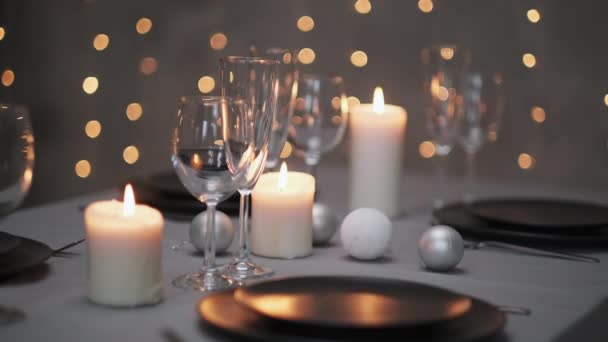 Table à manger festif servi. Beaux plats, nappes, verres à vin et assiettes grises. Bougies et une guirlande en arrière-plan. Décoration minimaliste de la salle à manger. Noël. — Video