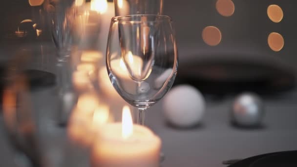 Tavolo da pranzo servito festivo. Bellissimi piatti, tovaglie, bicchieri di vino e piatti grigi. Candele e ghirlanda sullo sfondo. Arredamento minimalista della sala da pranzo. Natale!. — Video Stock