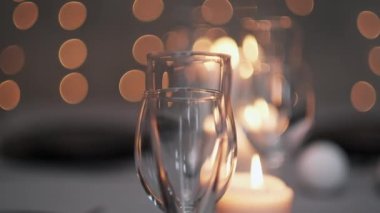 Şenlikli servis edilen yemek masası. Güzel yemekler, masa örtüleri, şarap bardakları ve gri tabaklar. Mumlar ve arka planda bir çelenk. Minimalist yemek odası dekorasyonu. Noel.