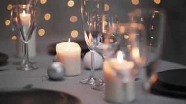 Şenlikli servis edilen yemek masası. Güzel yemekler, masa örtüleri, şarap bardakları ve gri tabaklar. Mumlar ve arka planda bir çelenk. Minimalist yemek odası dekorasyonu. Noel.