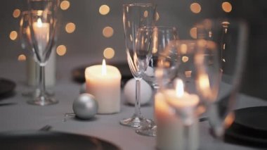 Şenlikli servis edilen yemek masası. Güzel yemekler, masa örtüleri, şarap bardakları ve gri tabaklar. Mumlar ve arka planda bir çelenk. Minimalist yemek odası dekorasyonu. Noel.