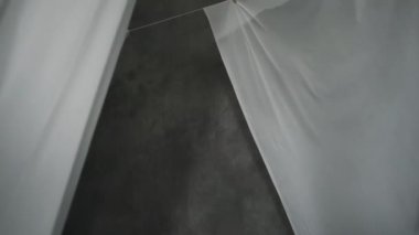 Beyaz kumaş çarşaflar ipteki mandallarla kurutulur. Dalgalı kumaş rüzgarda sallanıyor. Soyut gri arkaplan.