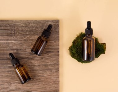 Seramik fayanslarda serum şişeleri ahşap desenli ve bej arkaplanda desenli. Yosun üzerinde bir şişe serum var. Sürdürülebilir yaşam tarzı konsepti, doğal kozmetik. Üst görünüm