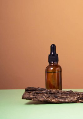 Ağacın kabuğunda serum camı şişesi. Bej ve yeşil arka plan. Sıvı deri ya da saç bakım ürünü. Doğal kozmetik konsepti. Ön görünüm, boşluğu kopyala.