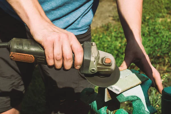 Electro grinding of a metal plate. Male hands holding a tool