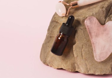 Şişede ve silindirde serum ya da öz, doğal bir taşın üzerinde gua sha masaj kazıyıcısı.