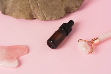 Şişede ve silindirde serum ya da öz, doğal bir taşın üzerinde gua sha masaj kazıyıcısı. Bencillik, güzellik ve sağlık konsepti.