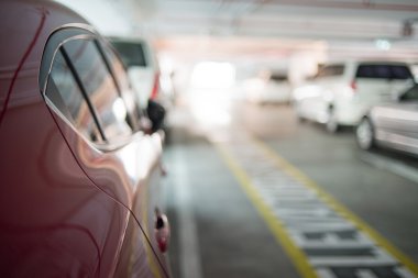 Kentsel kapalı otopark yanında kırmızı araba arka plan bulanıklık