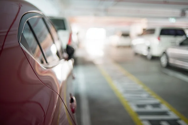 Abstract blur urban indoor car park beside red car background — Stock Photo, Image