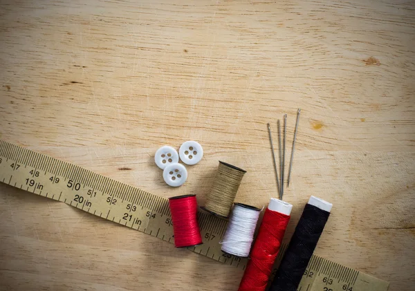 Швейный комплект с ниткой и иглами на деревянном фоне — стоковое фото