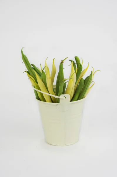 Fresh picked green beans spilling from a rustic bucket laying on — Stock Photo, Image