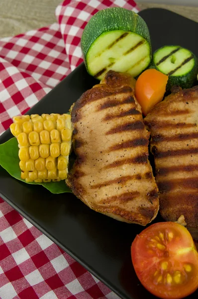 Carne di maiale alla griglia con verdure arrosto su piatto nero. BBQ — Foto Stock