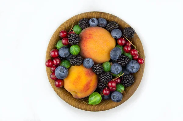 Frutos e bagas em um prato de madeira, groselha espinhosa, amora, pe — Fotografia de Stock