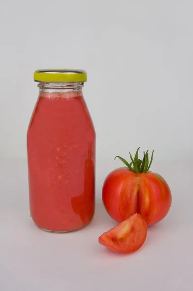 Bottle of tomato juice and ripe tomatoes. — Stock Photo, Image