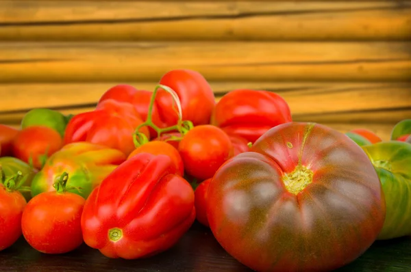 Fräsch ljus tomat med blad på trä bakgrund — Stockfoto