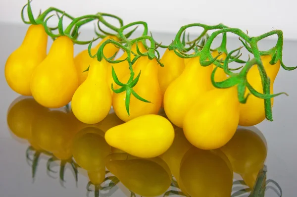 Tomates amarillos sobre fondo de vidrio con primer plano de reflexión — Foto de Stock
