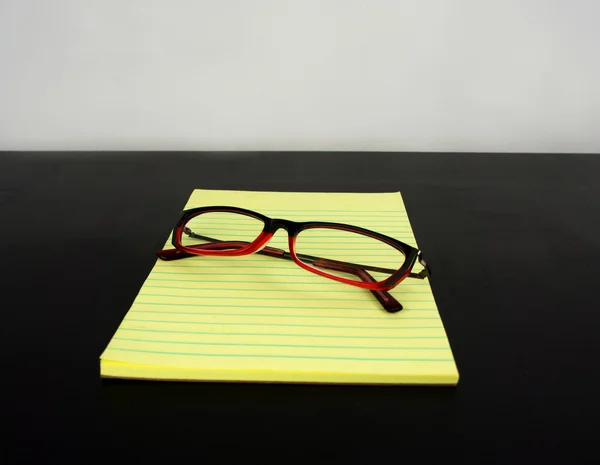 Yellow legal pad on a black table with glasses — Stock Photo, Image