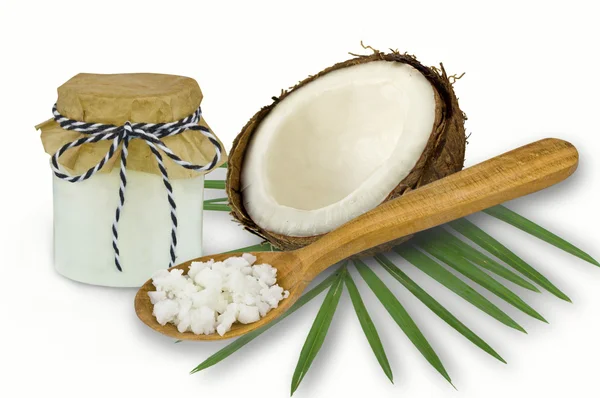 Aceite de coco fresco en cristalería y cuchara de madera sobre un respaldo blanco — Foto de Stock