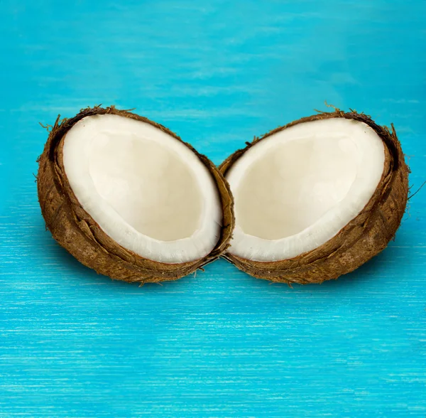 Dos mitades de coco sobre un fondo azul de madera — Foto de Stock