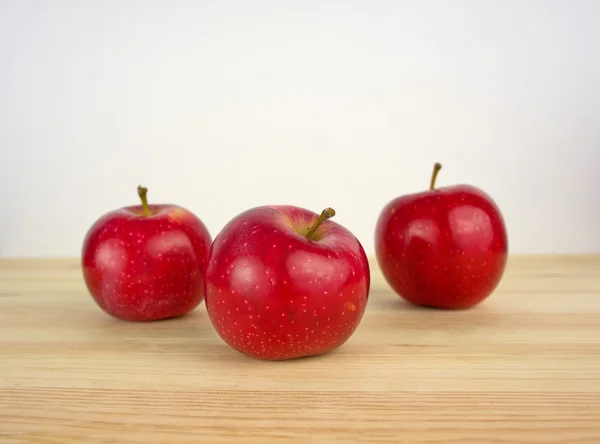 Ahşap zemin üzerinde üç elma — Stok fotoğraf
