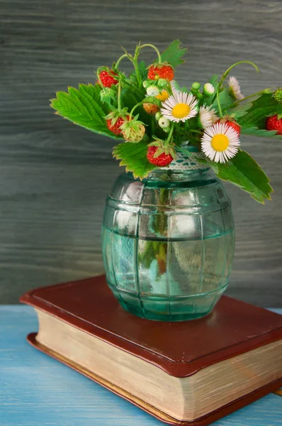 Strawberry with flowers in a glass vase with books in vintage st — Stock Photo, Image