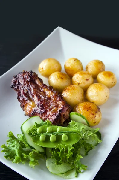 Мясо на гриле с жареной картошкой и овощным салатом — стоковое фото