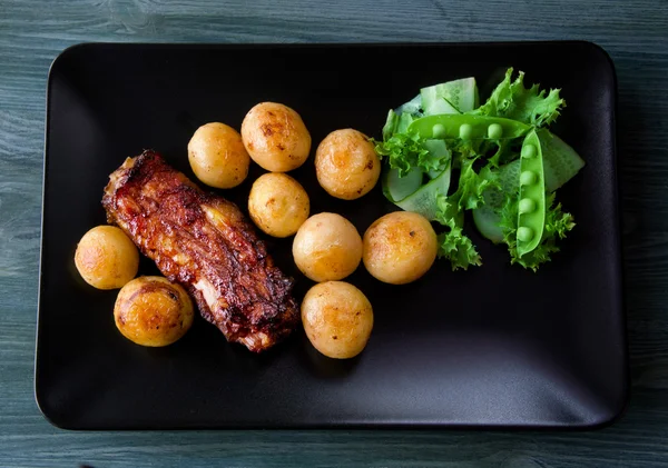 Plato principal gourmet con costillas de cerdo asado y patatas fritas en una b — Foto de Stock