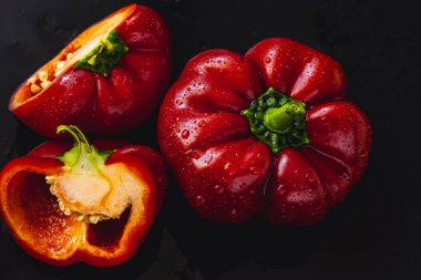 Siyah arka planda taze kırmızı dolma biber. Üst görünüm Tropik soyut arkaplan. Biber sebzelerini su damlalarıyla kabartın.