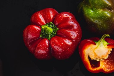 Siyah arka planda taze kırmızı dolma biber. Üst görünüm Tropik soyut arkaplan. Biber sebzelerini su damlalarıyla kabartın.
