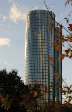 Sonbahar günü Riga 'daki Kipsala Kuleleri' nde. Sonbahar öğleden sonra gökyüzünü ve beyaz bulutları yansıtan iki uzun, yuvarlak gökdelen.